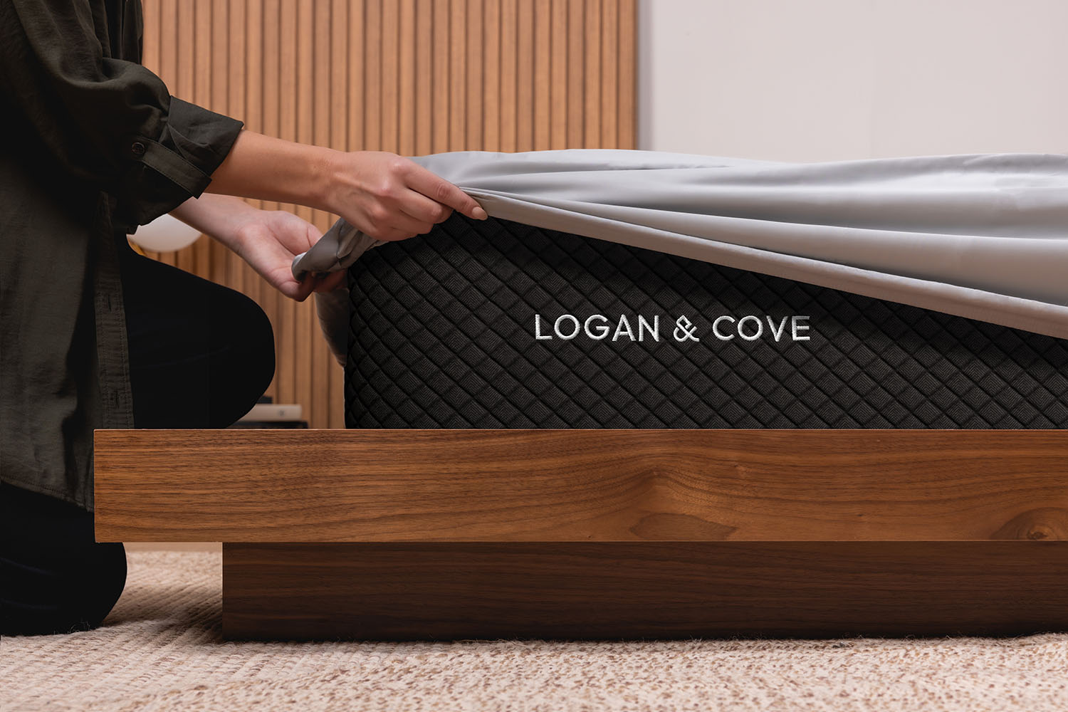 Woman pulling the fitted sheet of her Logan & Cove Bamboo Sheets over the corner on a mattress