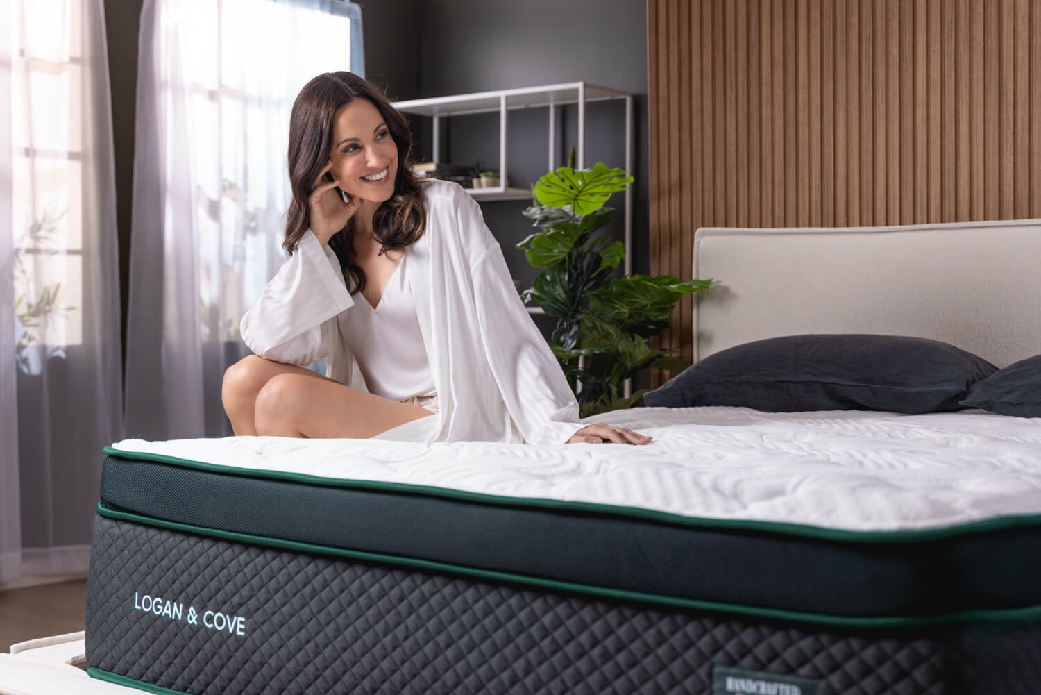 Woman smiling while sitting on her Logan & Cove mattress